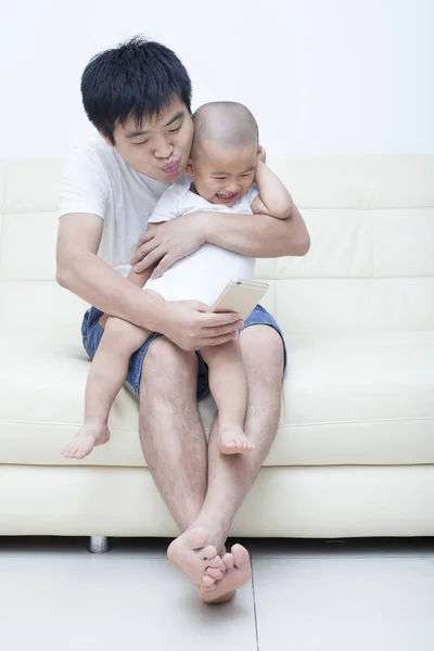 Chinesischer Vater und Sohn machen Selfie auf Sofa — Stockfoto