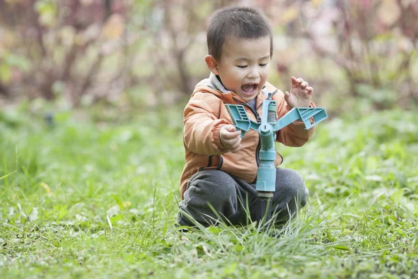 Bir musluk otların arasında oynarken mutlu bebek çocuk