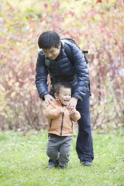 Mutlu gerçek baba ve oğul çayırda oynarken