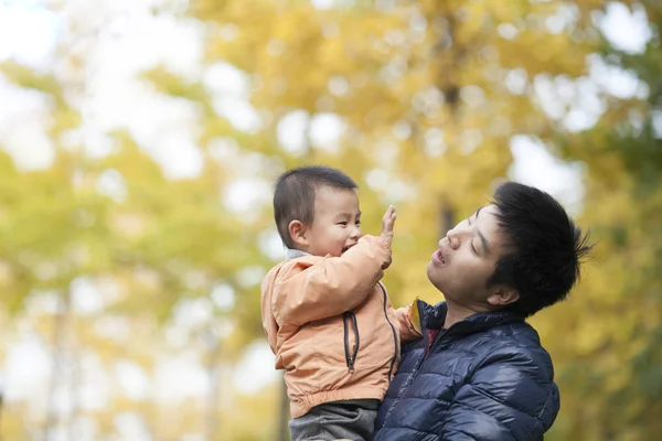 Glücklicher echter Vater und Sohn beim Spielen vor Ginkgo-Bäumen — Stockfoto