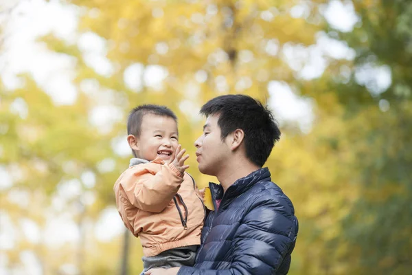 Glücklicher echter Vater und Sohn beim Spielen vor Ginkgo-Bäumen — Stockfoto