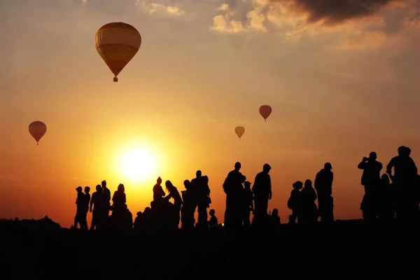 Σιλουέτες των ανθρώπων ενάντια στο σκηνικό αερόπλοια και sunse — Φωτογραφία Αρχείου
