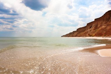  Mavi gökyüzü, turkuaz deniz, kumsal ve dağlar. 
