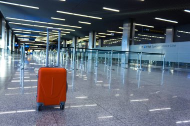 Havaalanında bekleme odasında turuncu bavul.
