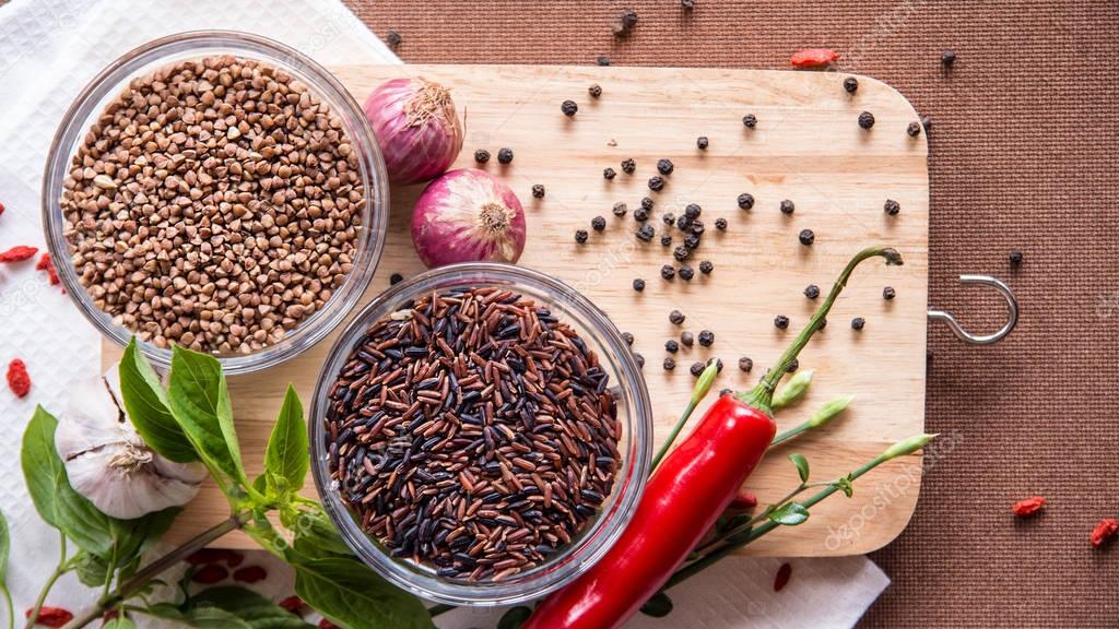 Trigo sarraceno, arroz negro, cebolla, chile rojo sobre fondo de madera ...