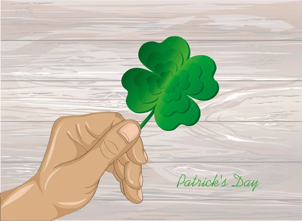 La mano sostiene el trébol adornado de cuatro hojas. Concepto de celebración St. Patrick — Vector de stock