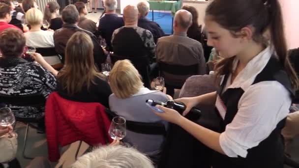 OLOMOUC, CZECH REPUBLIC, OCTOBER 7, 2017: Degustation and evaluation of wine quality in a large group of people. A young woman charming, pours wine into glasses — Stock Video