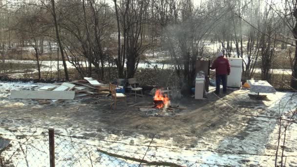 Olomouc, Tjeckien, 29 januari 2018: hemlösa stackars brinnande trä ombord och skapa eld för att värma sig i vinter snön, avger det radio och börja, bor i ett ark trä metall chalet — Stockvideo