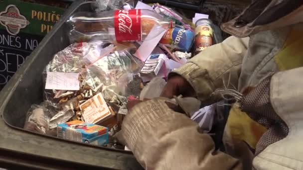 OLOMOUC, CZECH REPUBLIC, 5 мая 2018 года: Бездомный выбирает остатки окурка грязными руками из мусорного ведра и кладет его в мешок. Цивилизация приносит бедность, желтуху — стоковое видео