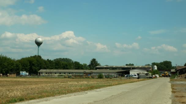OLOMOUC, REPÚBLICA CHECA, 25 de maio de 2019: Torre de reservatório de água com cúpula na colina para fazenda. Um homem em motocicleta de rodas claras em seu caminho lavoura onde ele é vacas — Vídeo de Stock