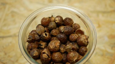 Soap nuts Indian soapberry or washnut glass jar cup, Sapindus mukorossi reetha or ritha from the soap tree shells are used to wash clothes to put drum washing machines. Nuts saponin plant fruit seeds clipart