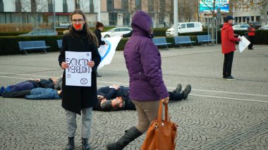 OLOMOUC, CZECH REPUBLIC, JANUARY 10, 2019: Extinction rebellion activist Anna Martinkova banner symbol circle hourglass warning, people lie on ground square showing death, demonstration