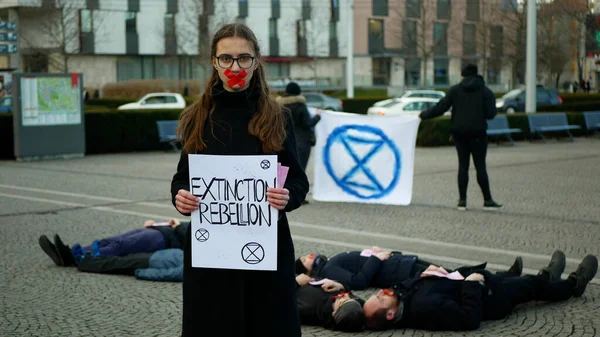 OLOMOUC, CZECH REPUBLIC, JANUARY 10, 2019: Extinction rebellion activist Anna Martinkova banner symbol circle hourglass warning, people lie on ground square showing death, demonstration — Stok fotoğraf