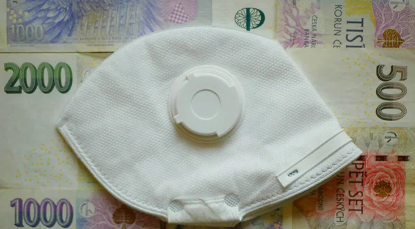 BRNO, CZECH REPUBLIC, 13 Mart 2020: FFP2 maskeli Coronavirus covid-19 ağız ve Çek para birimi banknotları üzerinde tıbbi sağlık. Kirliliğe karşı koruma, virüs gribi sars cov 2. İnsanlar enfeksiyon kapma riskine karşı önlem alıyorlar
