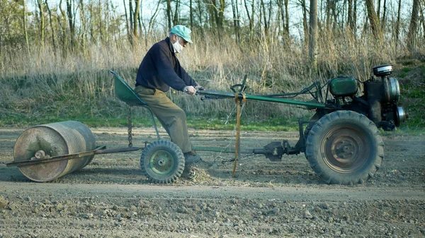 OLOMOUC, TSJECHIË, 21 maart 2020: Gezichtsmasker coronavirus risico covid-19 sars cov 2 sjaal sjaal roller rollen landbouwwerktuig afvlakking land veld klei bodem trekker grimmige historische home made — Stockfoto