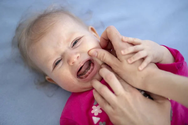 Crying baby in pain examined by mother