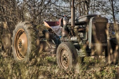 Güneşli bir günde, tarlada paslı bir traktör.