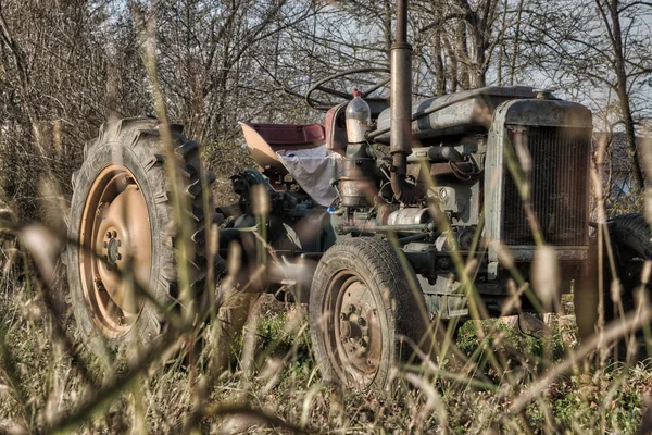 Trator enferrujado velho em um campo em um dia ensolarado — Fotografia de Stock