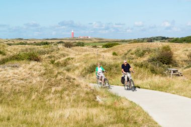 Seniors riding bicycles in dunes of Texel, Netherlands clipart
