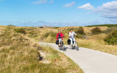 People cycling in dunes of Texel, Netherlands clipart