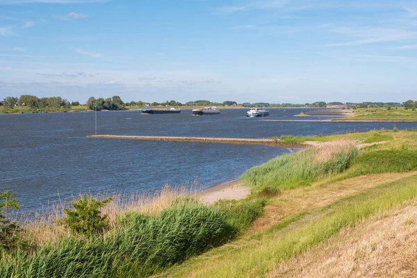 Panorama of river Waal with groynes and inland waterway shipping from dike on south bank near  Zuilichem, Bommelerwaard, Gelderland, Netherlands