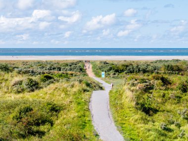 Kuzey Denizi kıyısındaki Schiermonnikoog plajında yürüyen insanlar.