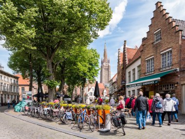 Bruges, Belçika 'daki Walplein Meydanı' nda insanlar, bisikletler ve restoranlar