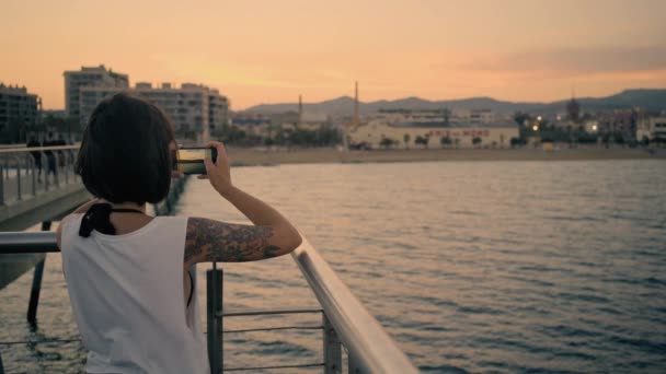 Mädchen benutzt Smartphone, während sie auf Seebrücke steht — Stockvideo