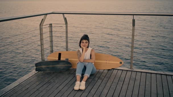 Дівчина сидить на дерев'яному пірсі — стокове відео