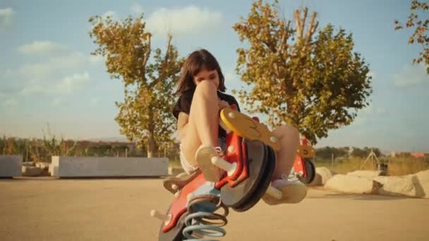 Brunette rides seesaw motorcycle on kids playground — Stock Video