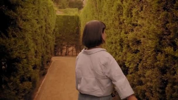 Брюнетка дівчина ходить всередині парку лабіринт — стокове відео