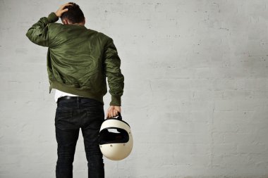 Beyaz kaskını tutan motosikletçi