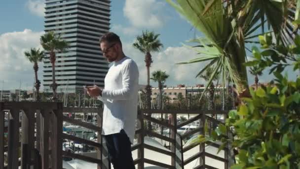 Junger Mann mit Smartphone neben Yachthafen — Stockvideo