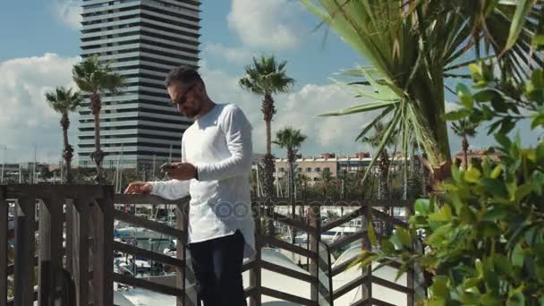 Jeune homme avec smartphone à côté de la marina — Video