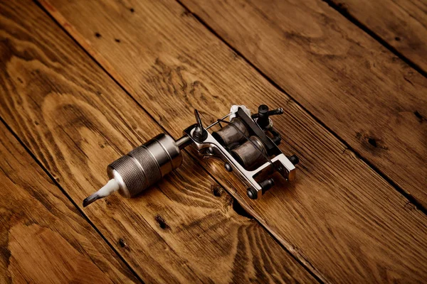 Tattoo gun on a rustic wooden table — Stock Photo, Image