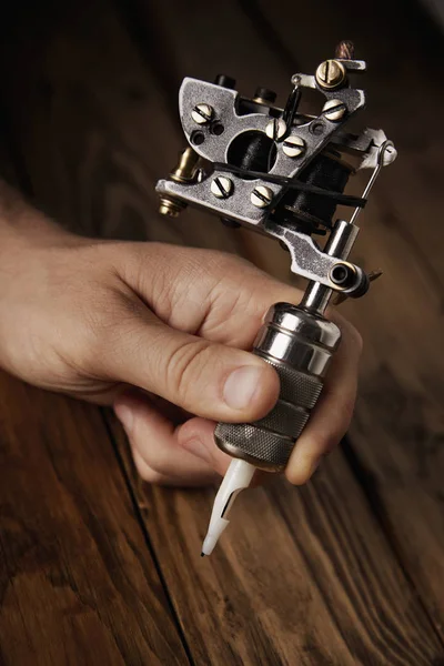 Primer plano de una mano de hombre con pistola de tatuaje — Foto de Stock