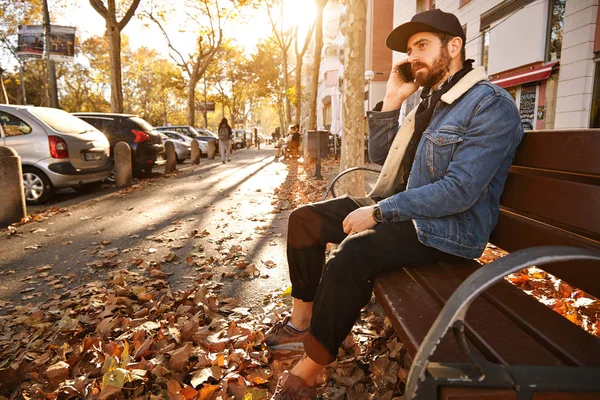 Hipster su una panchina con smartphone — Foto Stock