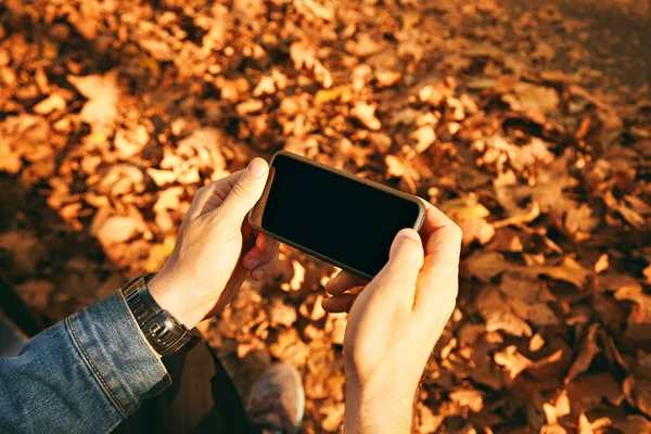 Homem tirando fotos de folhas de outono com smartphone — Fotografia de Stock