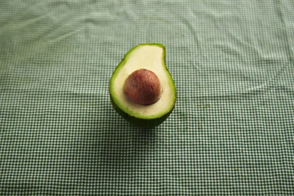 Avocadohälfte auf karierter Tischdecke — Stockfoto