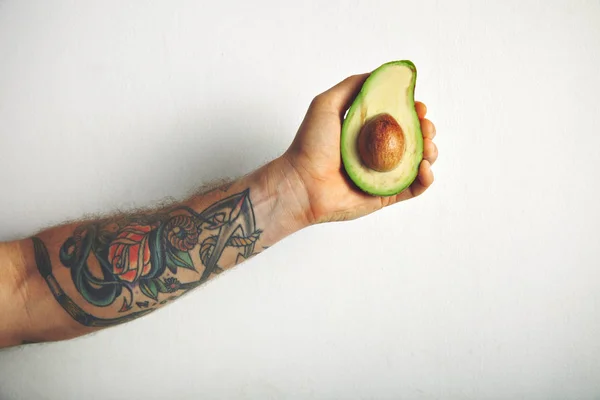 Männerarm mit halber Avocado — Stockfoto