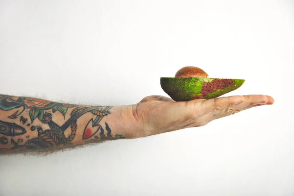Mans arm with half of avocado — Stock Photo, Image