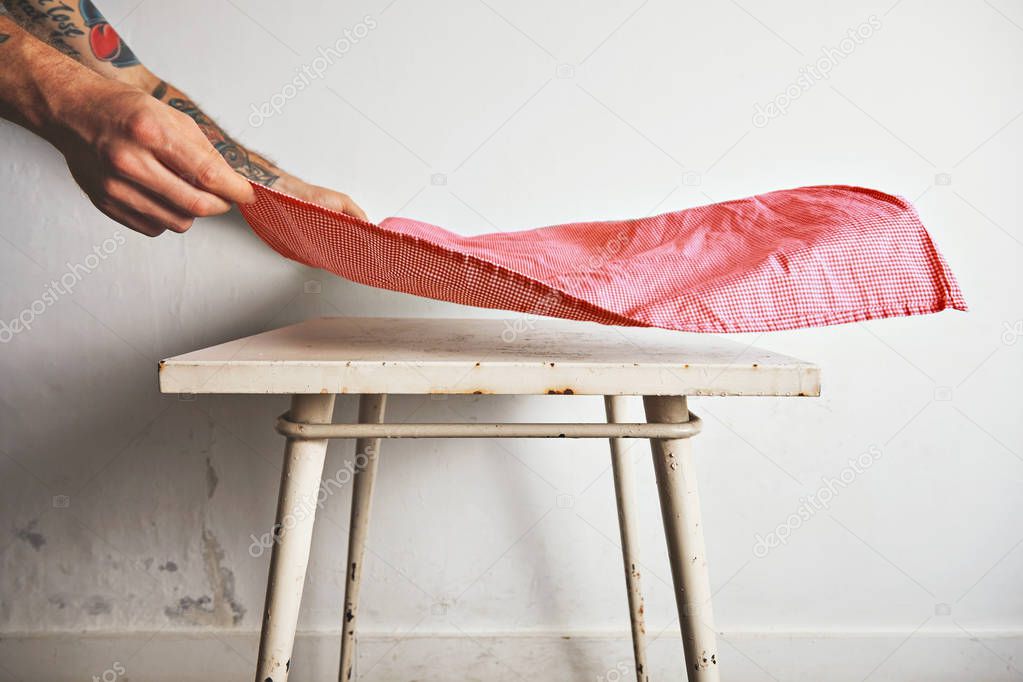 Putting tablecloth on old white table