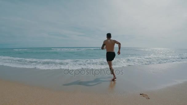 Человек бежит в океане, чтобы искупаться — стоковое видео