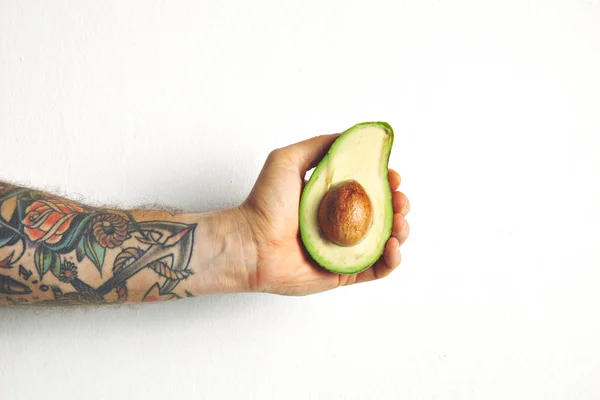 Männerarm mit halber Avocado — Stockfoto