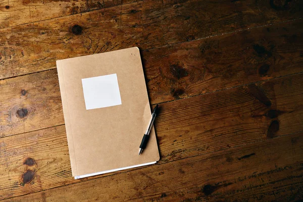 Unlabeled journal and a pen on  wooden table — Stock Photo, Image