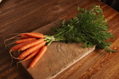Bunch of carrots on an old cutting board clipart