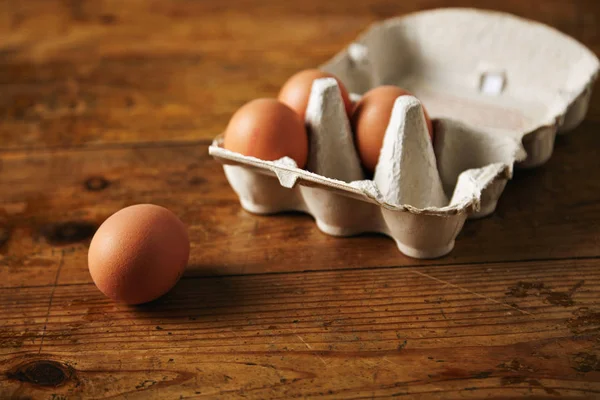 Karton mit Eiern auf einem Holztisch — Stockfoto
