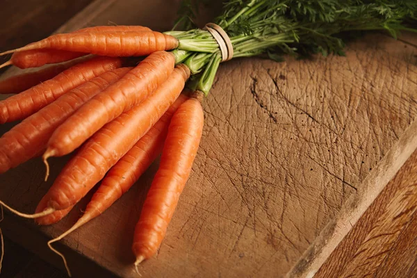 O grămadă de morcovi pe o placă veche de tăiere — Fotografie, imagine de stoc