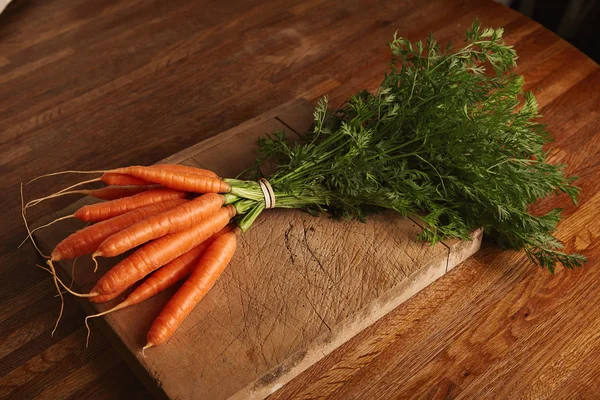 Manojo de zanahorias en una vieja tabla de cortar —  Fotos de Stock