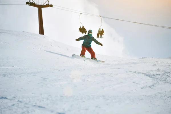 Flickan lär sig snowboard i bergen på vintern — Stockfoto